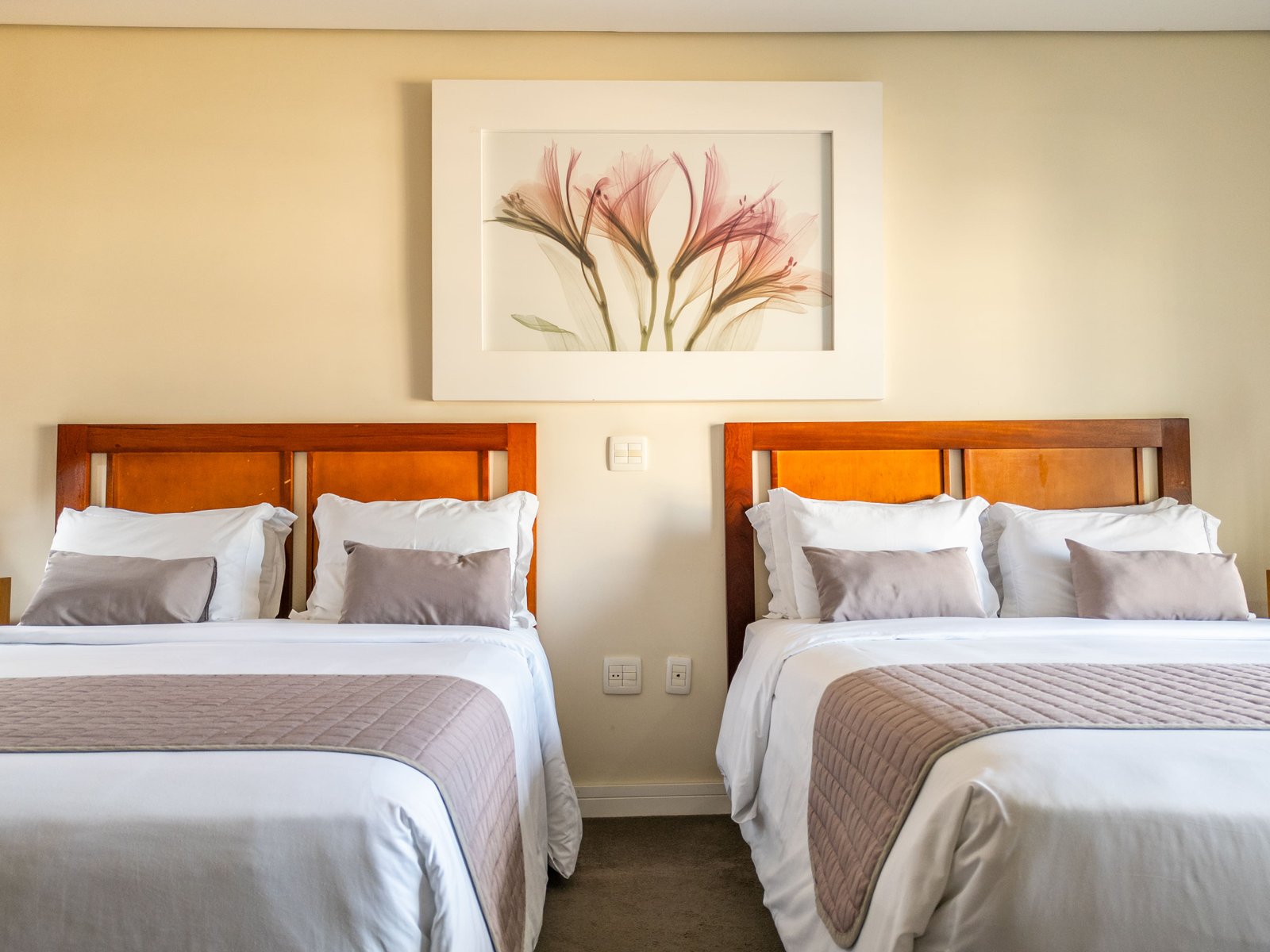 Suíte ampla com duas camas de casal king size, no mesmo ambiente, com sacada e vista para a piscina.